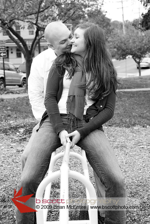 Black and white image of a couple having fun riding a seesaw.