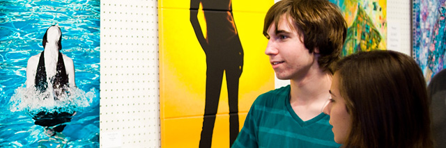 Young couple views large canvas artwork at fashion show exhibit.