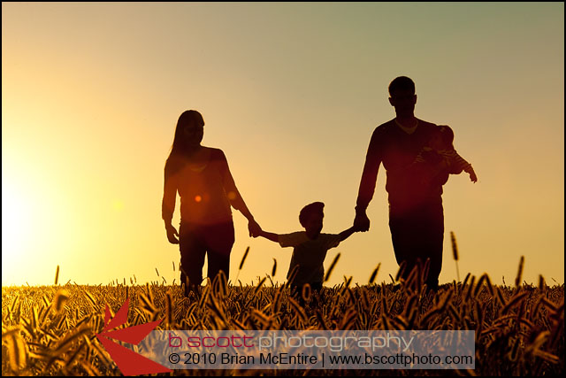 Family walks through grassy field in Frederick, MD, silhouetted by setting sun.