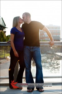Couple kisses, with sun at their back, on a bridge over Carroll Creek in Frederick, MD.